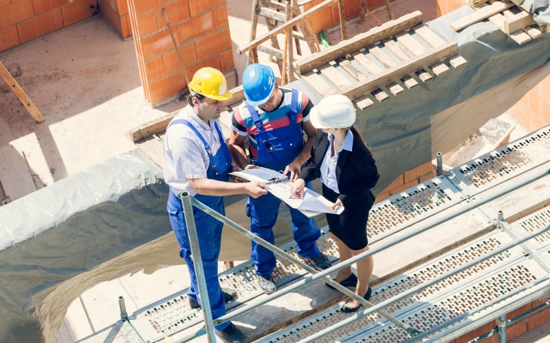 Bauarbeiter auf einer Baustelle schauen sich einen Bauplan an